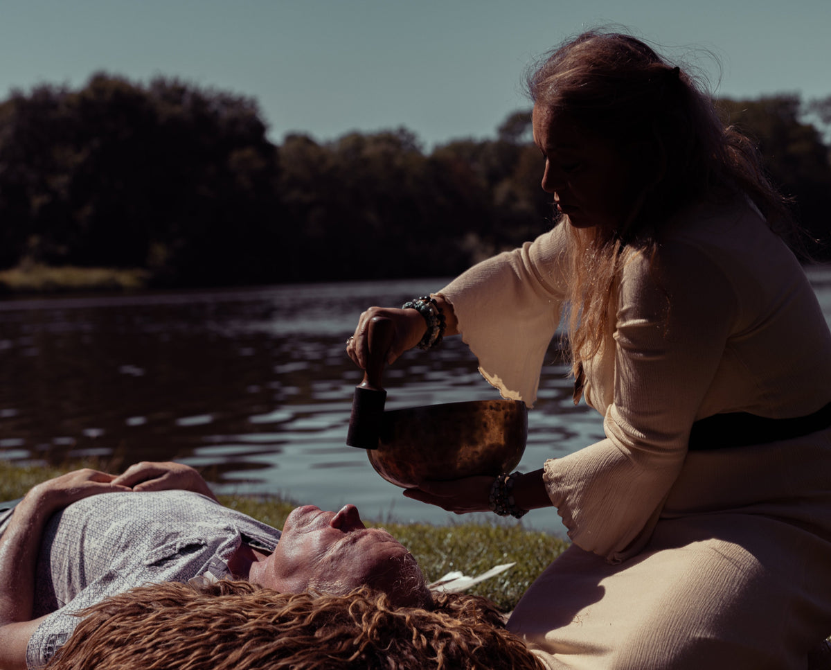 Spiritual Woman healing man with sound healing with a singing bowl in the forest